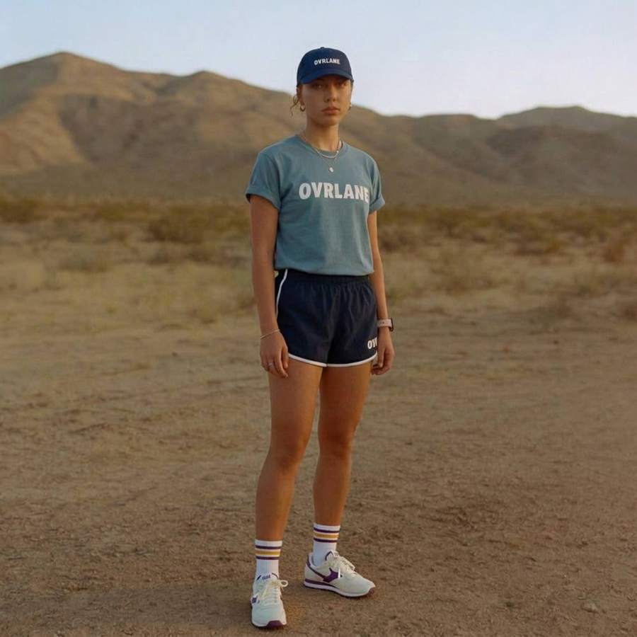 AI-generated outdoor fashion photograph of a woman in a cap and teal t-shirt in the desert
